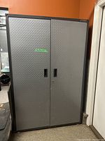 Front view of closed cabinet showing gray diamond-plate textured doors and recessed handles.