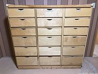 Front view of wood storage cabinet with 18 drawers, showing labels on some drawers such as 'Small Collectibles', 'Candles & Holders', and 'Party Supplies'.