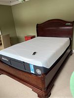 Queen-size mattress on adjustable wooden bed frame with remote control visible