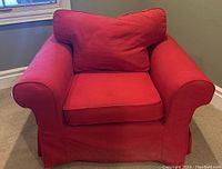 Front view of red slipcover armchair showing loose seat and back cushions, rolled arms and pleated skirt
