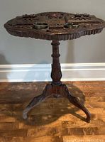 Full frontal view of carved walnut table on tripod base
