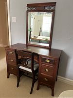 Full view of dark wood vanity table with attached mirror and side chair