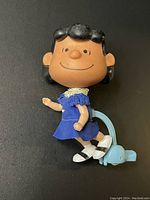 Front view of Lucy Peanuts toy with blue dress and walking mechanism.