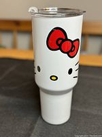 Front view of white stainless steel Hello Kitty tumbler showing face print with red bow and clear lid.