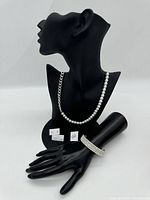 Photo showing the pearl necklace alongside silver-tone chain necklace, bracelet on hand model, and 3 pairs of stud earrings on display card.