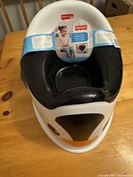 Front and side view showing design and packaging of Fisher-Price Penguin Potty Chair with black seat and penguin face decoration on white plastic.