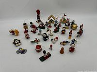 Photo showing the entire lot of 36 small wooden Christmas and winter holiday ornaments arranged on a white background.