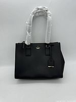 Front view of black leather bag with protective wrap on handles