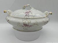 Front angle showing the oval covered vegetable dish with floral pattern and gold trim