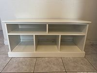 Front view of white shelving unit, showing two compartments on top and three compartments on bottom.