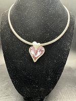 Front view of the silvertone chain necklace choker featuring an asymmetrical pink heart pendant with faceted design on a black display bust.