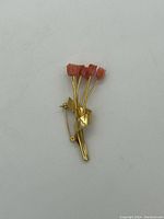 Front view of vintage brooch pin with five coral flower buds and gold tone stems wrapped with a ribbon detail