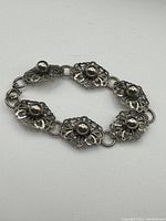 Photo of vintage fine silver filigree bracelet laid flat showing the linked filigree sections and silver ball centers.
