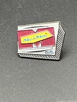 Front close-up of the MuchMusic pin showing the logo and textured silver base.