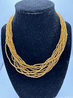 Full view of the vintage multi strand gold bead necklace arranged on display bust.
