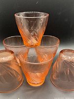 Front view of vintage pink swirl Depression glass cups stacked and arranged to show design and color.
