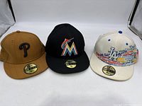 Front view of three MLB New Era fitted hats for Phillies, Marlins, and Dodgers.