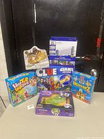 Full view of all boxed games and toy set displayed together including Clue, Hot Tub High Dive, Hedbanz, Fructus puzzle, and a 4-piece magnetic toy set.