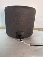 Image of the back of the Amazon Echo showing fabric covering and power cord with red indicator light.