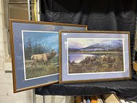 Two framed wildlife art prints displayed side by side, one showing a bull elk and the other a moose scene in natural landscapes.