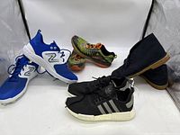 Wide shot showing five pairs of men's shoes including New Balance cleats, Adidas sneakers, Hoka shoes, Charles F Stead shoes.