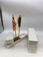 Three desk flag displays with two flags each on thin gold poles with a rectangular base, flags labeled as Pennsylvania, Delaware, and New Jersey.
