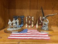 Two Danbury Mint statues displayed with USA letters backdrop and a flag, showing the complete lot