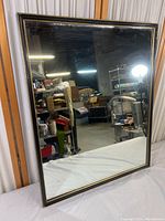 Full view of a rectangular heavy-duty mirror with black and gold frame, reflecting a storage area.