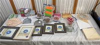 Full display of picture frames, crafting materials including shredded paper, wood paddle board, multi-colored foam sticks, and metal frames.