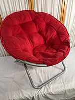 Photo showing the full round red padded cushion on foldable grey metal frame chair.