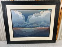 Framed landscape lithograph depicting clouds and mountain ranges with visible blemishes on the print and damage to the canvas surface.