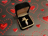 Snake ring in black velvet jewelry box with heart-patterned background