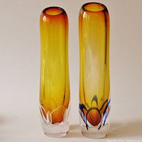 Photo showing two tall cylindrical amber glass vases side by side, highlighting their overall color and shape.