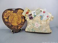 Photo showing the painted silk pillow holding four antique Valentine postcards alongside the heart-shaped plaque