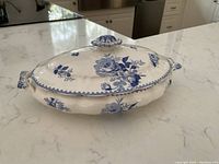 Side angle of Booths England vintage covered serving dish showing blue floral pattern on white base with handles and lid knob.