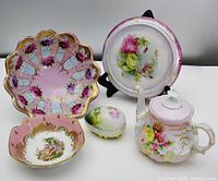 Lot showing all five porcelain pieces together on display including teapot, two bowls, trinket box, and trivet.