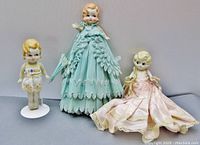 All three bisque dolls standing together showing front view with clothing and accessories