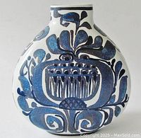 Front view of the vase showing stylized blue floral decoration on white ceramic surface.