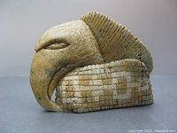 Side profile showing stylized eagle head and grid-patterned base