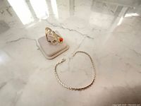 Photo showing the snake motif ring with coral bead on display stand next to the sterling silver chain bracelet