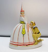 Full side view of the lamp showing knight kneeling by maiden in conical hat and ornate dress. The base is oval and white with minor chips.