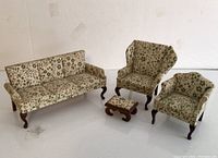 Full set of four vintage miniature dollhouse furniture pieces: sofa, wingchair, armchair, and footstool with floral upholstery and wooden cabriole legs on white background