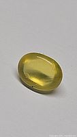 Front angled view of oval cabochon yellow fire opal gemstone showing smooth polished surface and deep yellow color.