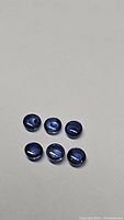 Photo clearly shows six round cabochon cut blue sapphire gemstones on a neutral background, illustrating color and shape.