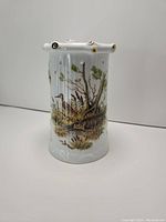 Side view of porcelain mug showing tree design with flying ducks and natural scene with gold accents.