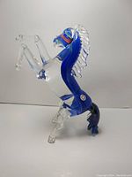 Side view of prancing horse Murano glass figurine showing clear and blue glass with detailed mane and tail.