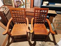 Two wooden antique chairs, lattice backs, curved armrests, wooden slatted seats, light wear, needing cleaning.