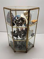 Glass display case with three shelves holding assorted items