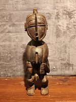 Front view of the carved wooden African statue showing detailed facial features and posture.