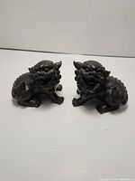 Front view of two Chinese Foo dog statues, showing facial details and posture